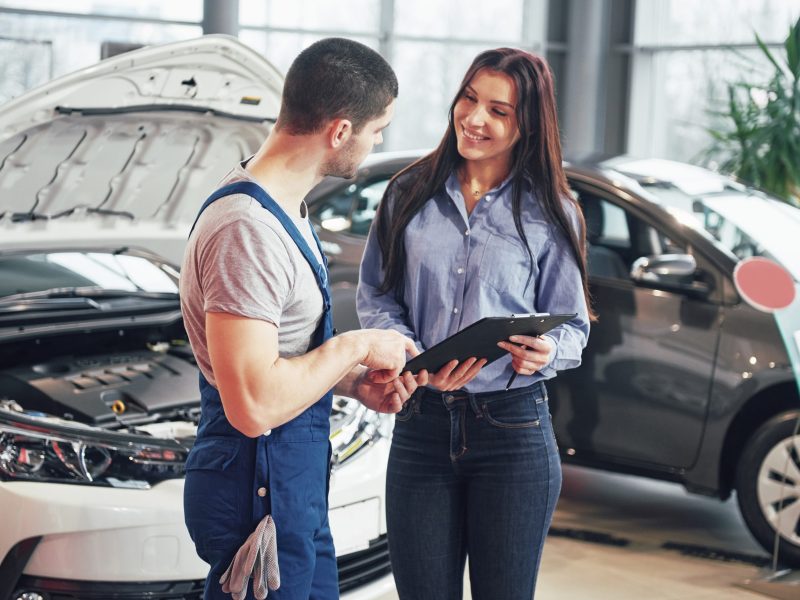 A man mechanic and woman customer discussing repairs done to her vehicle.